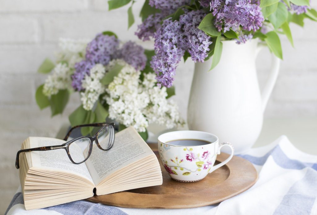 Livre posé sur une table à côté d'un bouquet de fleurs et d'une tasse