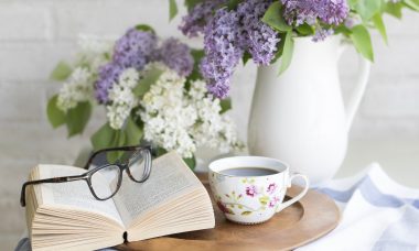 Livre posé sur une table à côté d'un bouquet de fleurs et d'une tasse