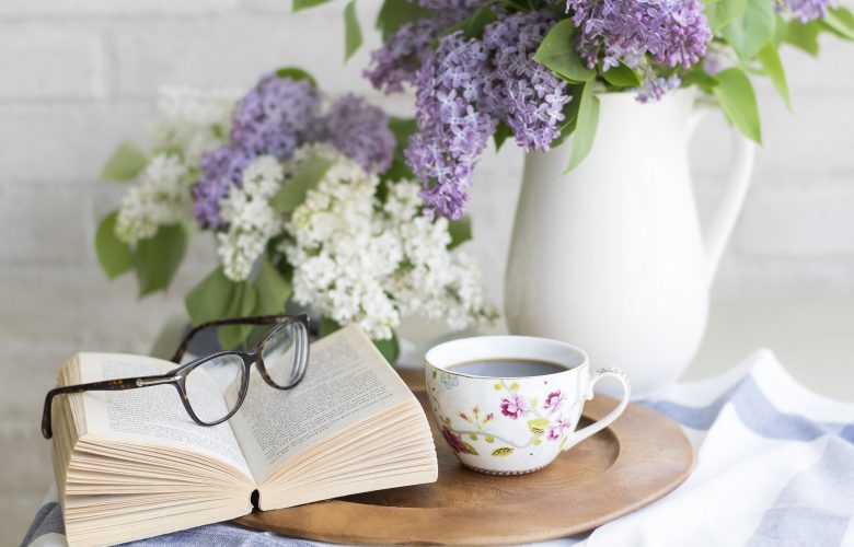 Livre posé sur une table à côté d'un bouquet de fleurs et d'une tasse